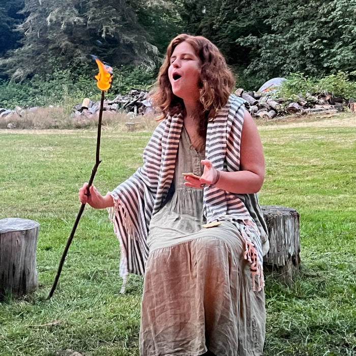 smiling redhead blowing on her flaming marshmallow